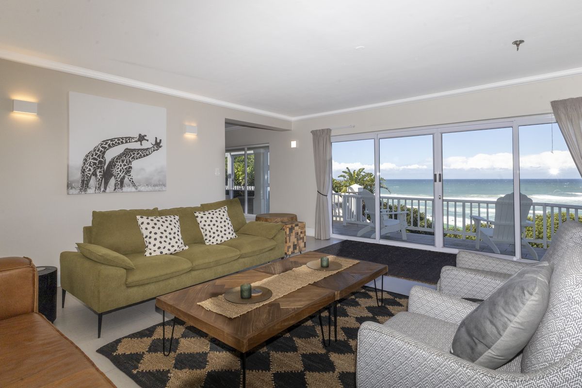 Spacious living room featuring large sliding glass doors that provide abundant natural light and direct access to a balcony with ocean views.