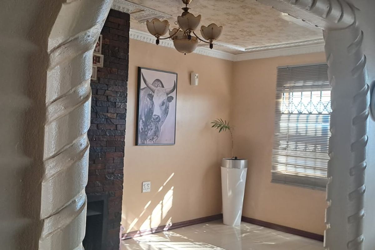 A living area featuring decorative plaster archways, a stone-clad fireplace, and tiled flooring, offering a distinct architectural character.