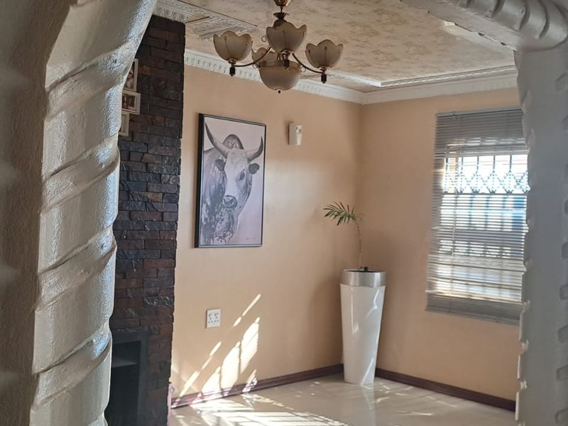 A living area featuring decorative plaster archways, a stone-clad fireplace, and tiled flooring, offering a distinct architectural character.