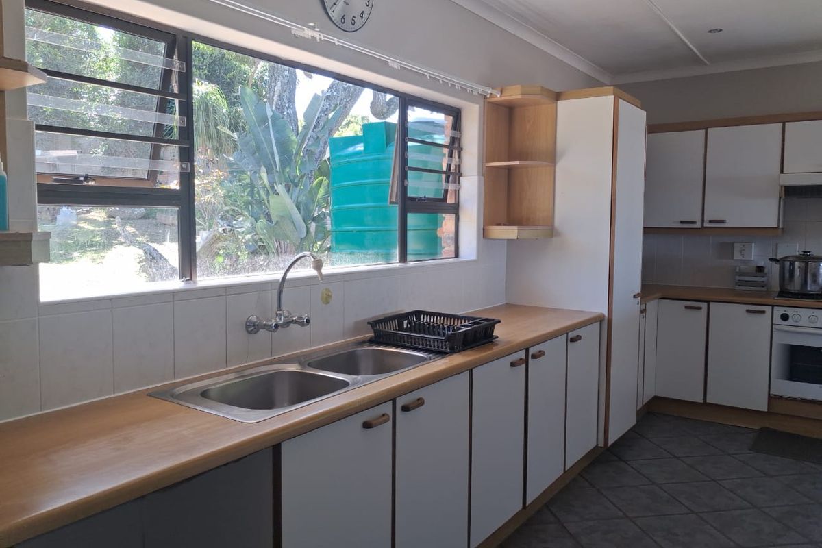 Functional kitchen featuring laminate countertops, double stainless steel sink, built-in oven, and ample cabinetry with views of the garden.