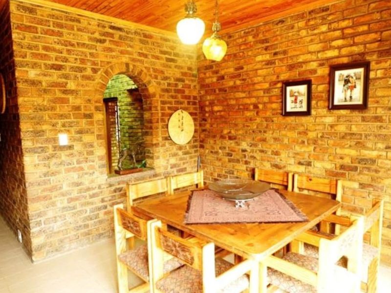 Dining area featuring rustic exposed brick walls, a warm timber ceiling, and a unique arched wall niche, creating a traditional and cozy atmosphere.