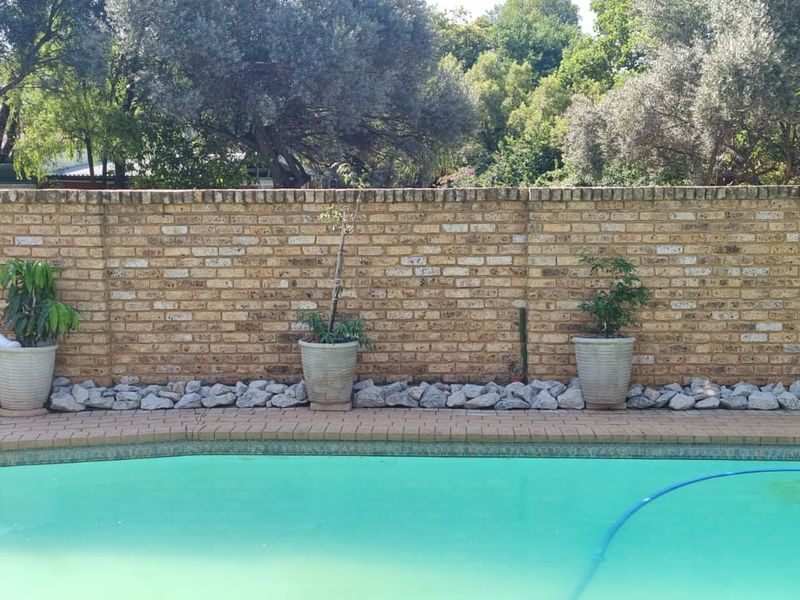A private swimming pool area featuring a paved surround and a solid brick boundary wall, providing a secure and enclosed outdoor space.