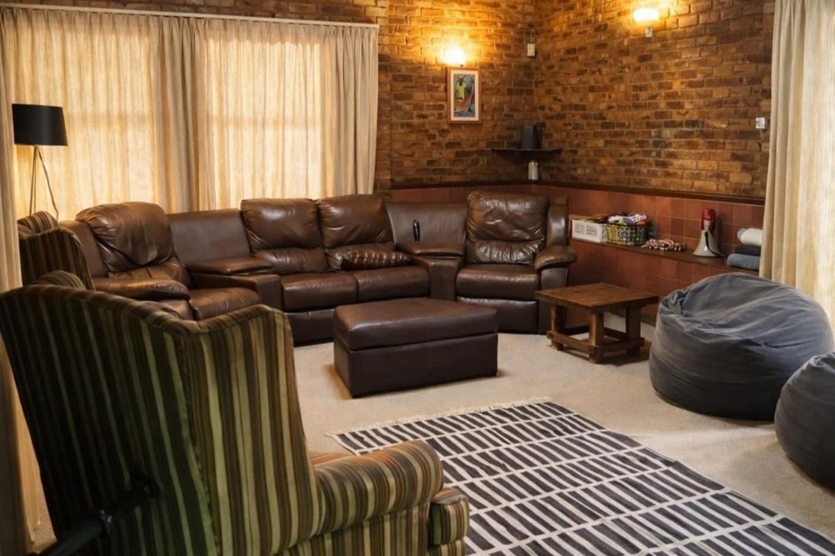 A cozy living room featuring exposed brick walls, tiled wainscoting, and warm wall-mounted lighting, creating a rustic and comfortable atmosphere.
