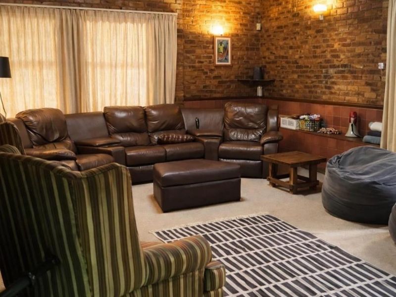 A cozy living room featuring exposed brick walls, tiled wainscoting, and warm wall-mounted lighting, creating a rustic and comfortable atmosphere.