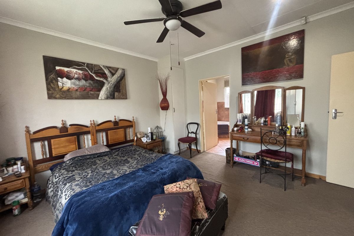 Spacious bedroom featuring a ceiling fan, built-in storage, and neutral wall finishes, with direct access to an adjoining bathroom.