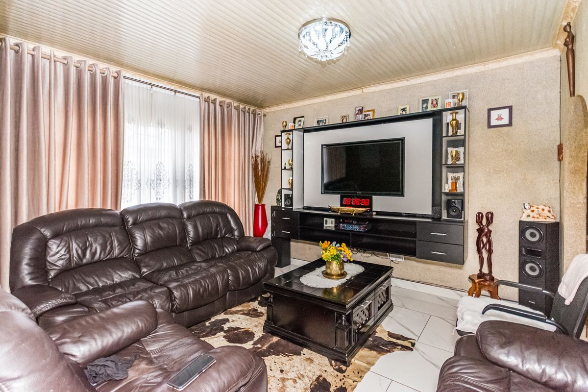 A living room featuring a built-in media wall unit, tiled flooring, and a textured ceiling finish.