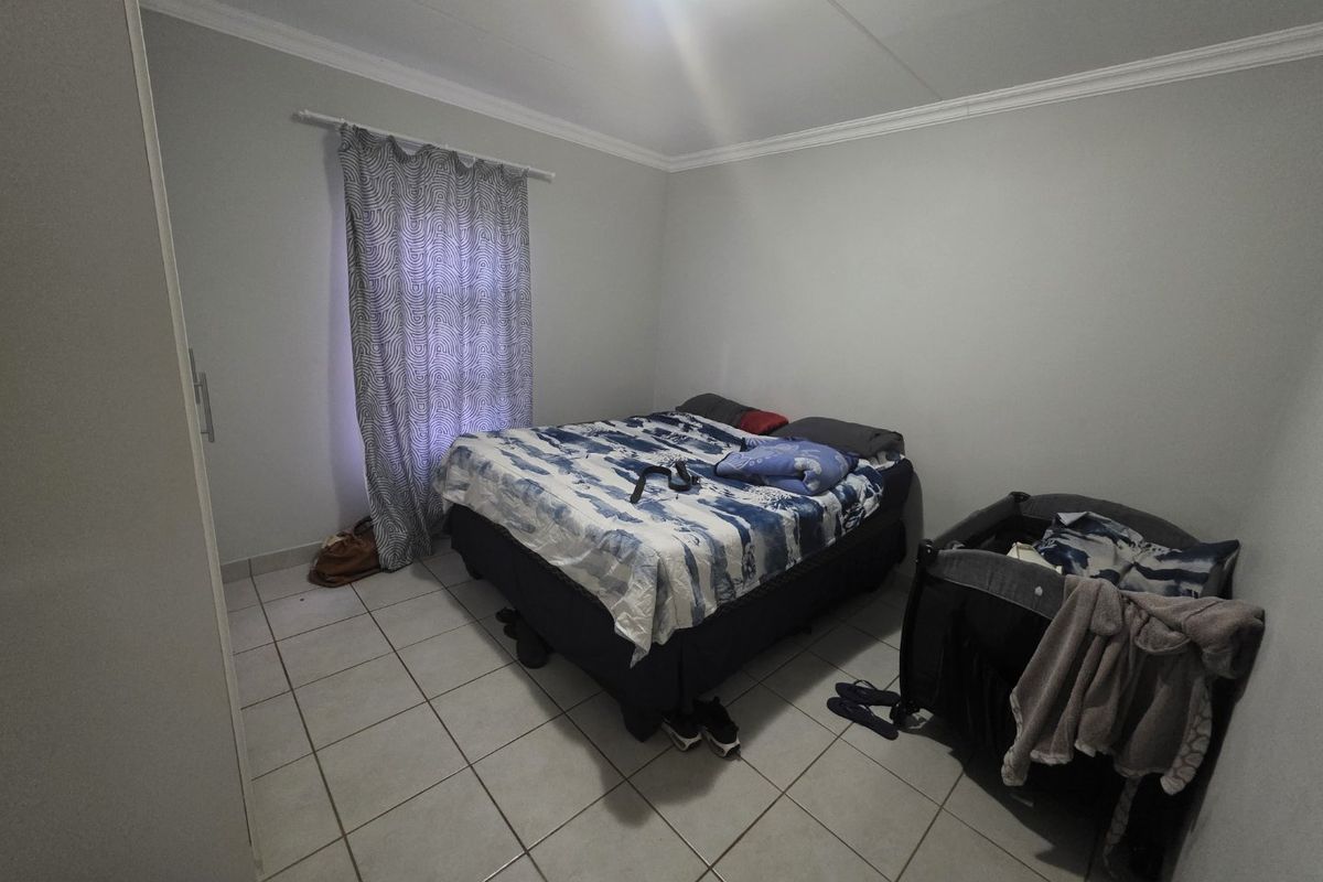 A functional bedroom featuring tiled flooring, built-in cupboard space, and neutral wall finishes.