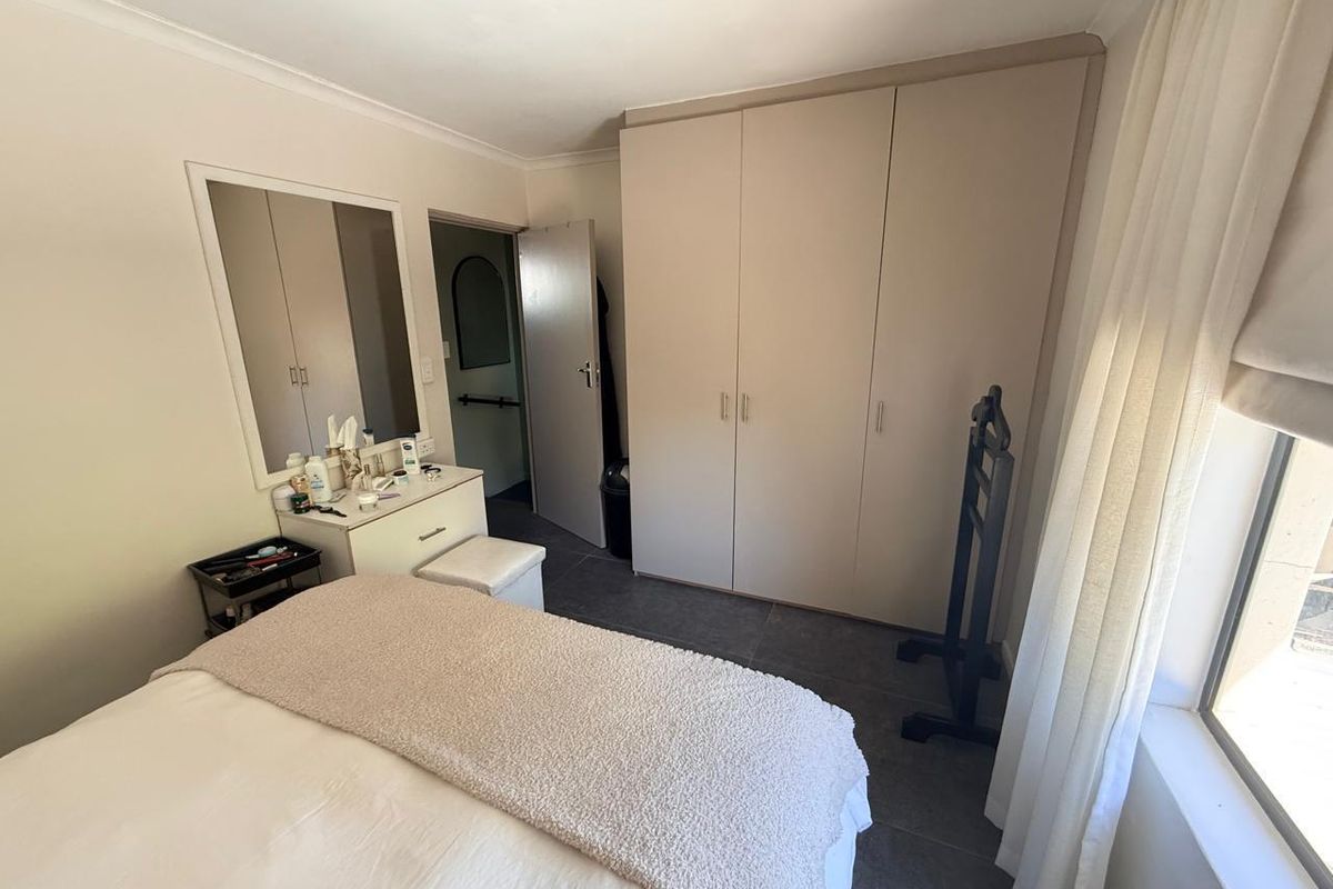 A bedroom featuring built-in cupboards, tiled flooring, and a vanity area with a wall-mounted mirror.