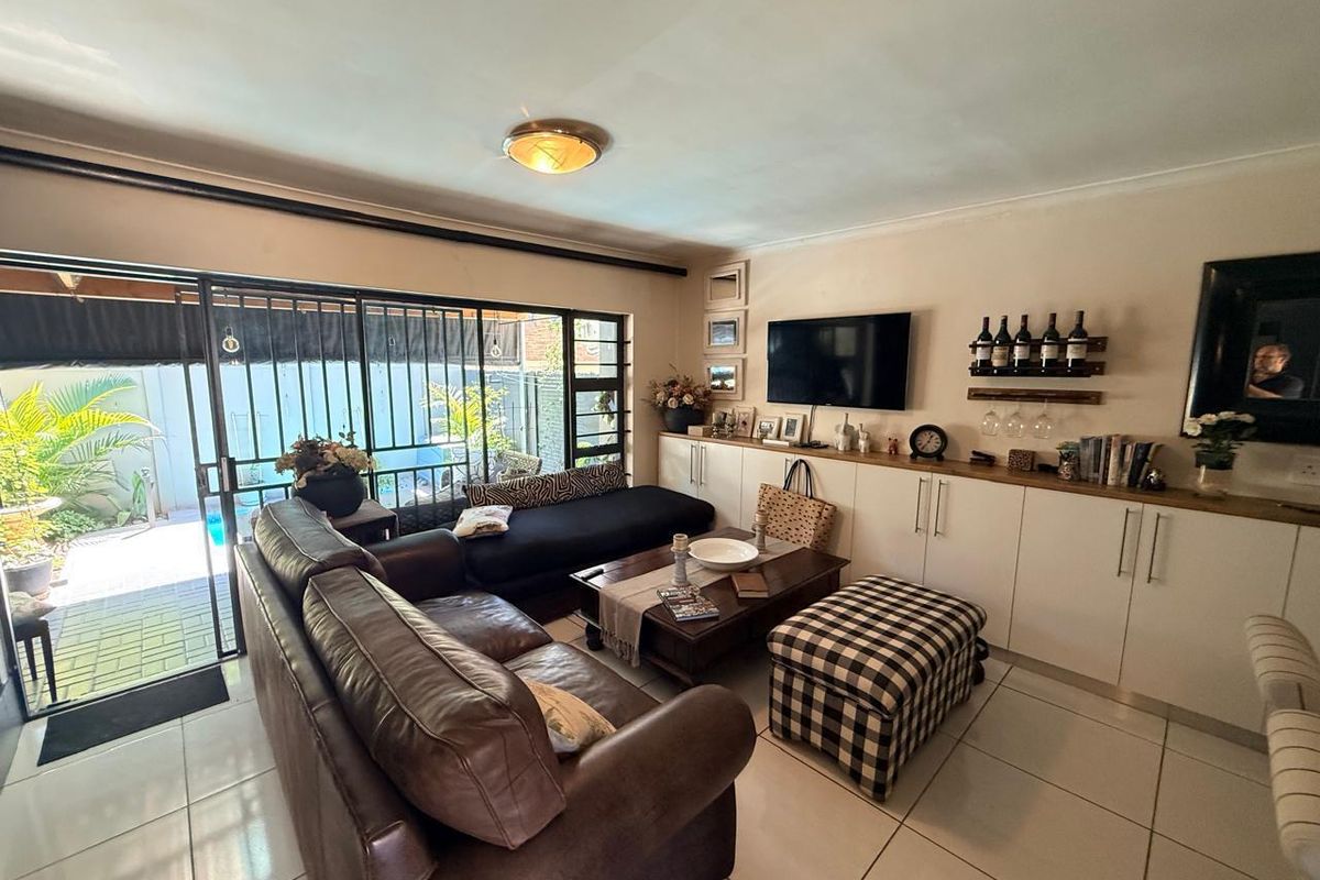 A comfortable living room featuring built-in cabinetry, tiled flooring, and large sliding glass doors providing direct access to the outdoor patio area.