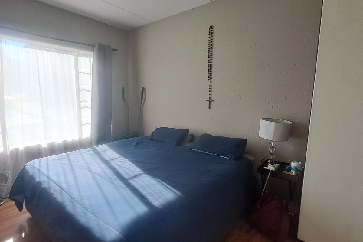 A bedroom featuring laminate flooring, a ceiling fan, and a built-in wardrobe, offering a functional space with natural light.