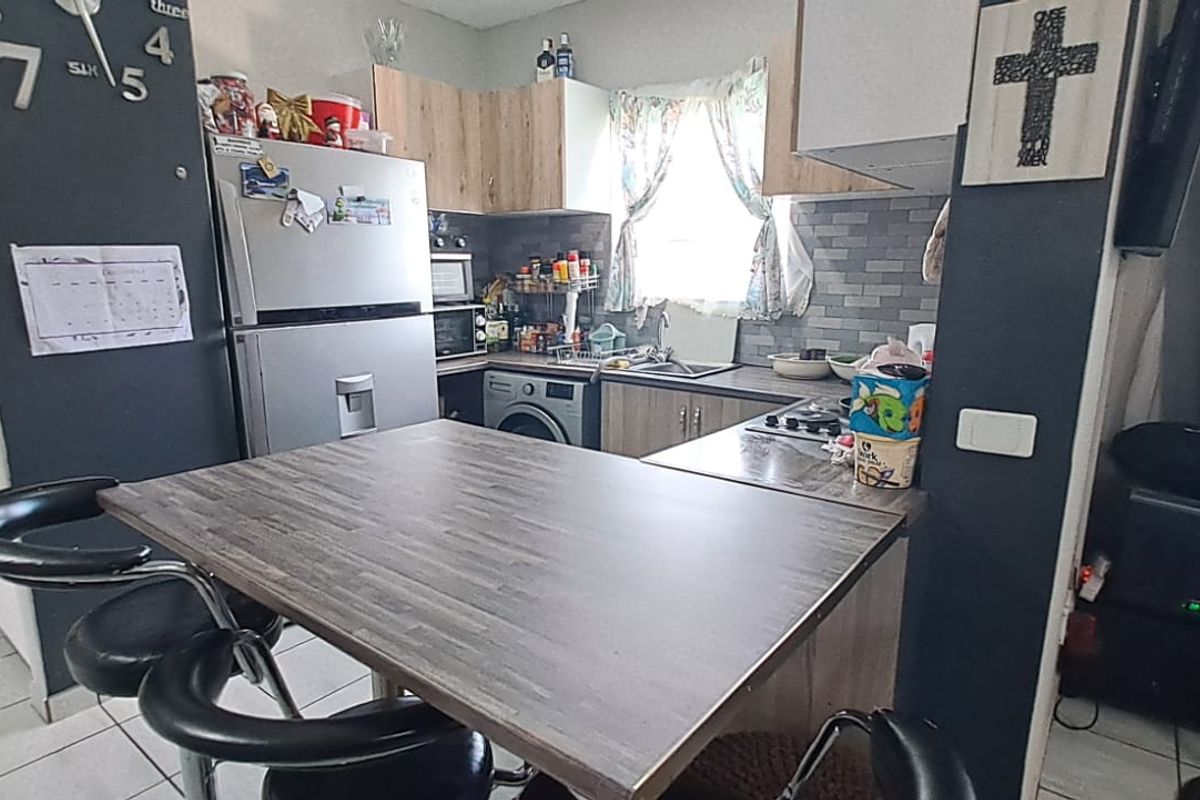 Compact kitchen featuring laminate cabinetry, tiled backsplash, built-in hob, and a functional breakfast bar area with tiled flooring.