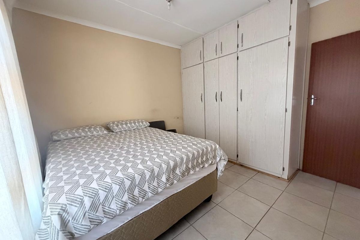 A functional bedroom featuring built-in cupboards and tiled flooring, offering a neutral canvas for potential interior updates.