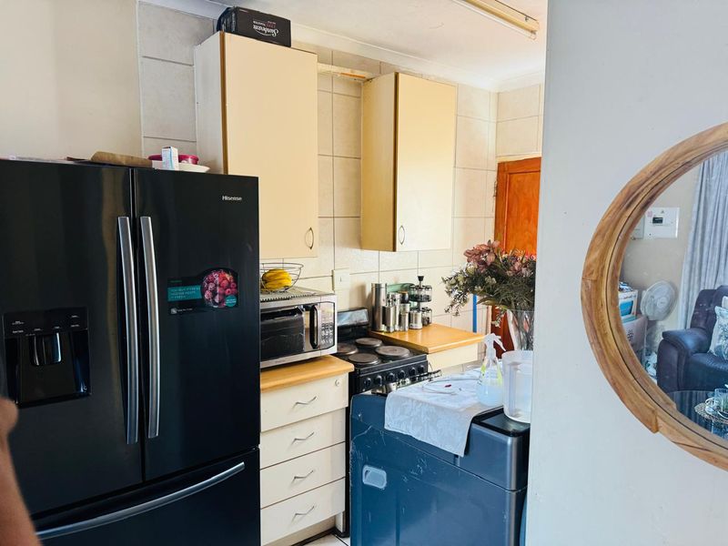 A compact kitchen featuring dated cabinetry, tiled backsplash, and a built-in electric stove, offering potential for a modern renovation.