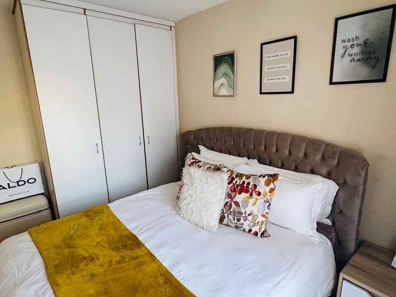 A cozy bedroom featuring a built-in wardrobe with white cabinetry and neutral wall finishes.