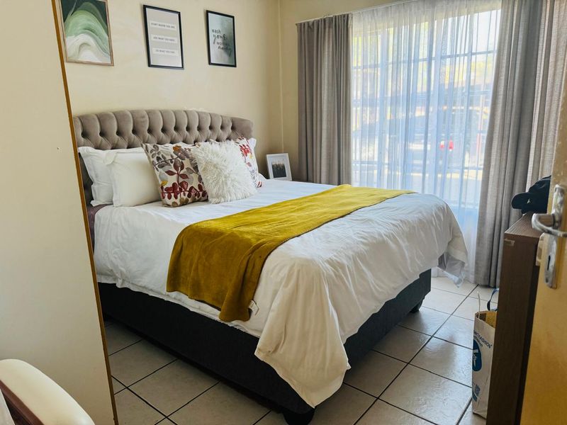 A functional bedroom featuring tiled flooring and a large sliding glass door that provides natural light.