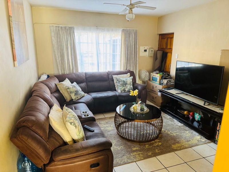 A living room featuring tiled flooring, a ceiling fan, and a sliding glass door providing natural light.