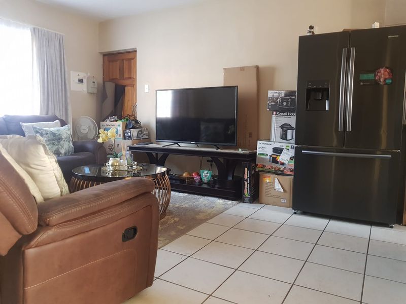 Open plan living area featuring tiled flooring and a functional layout, suitable for a combined lounge and kitchen space.
