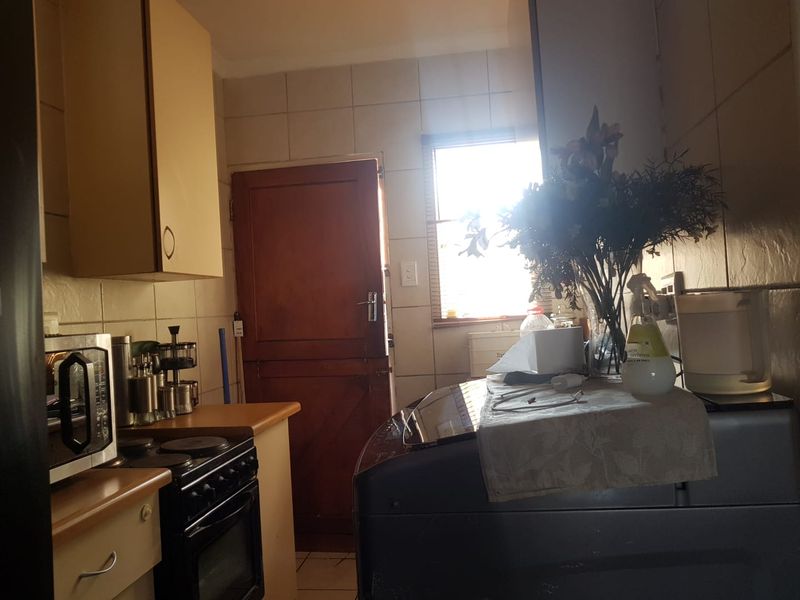 A functional kitchen area featuring built-in cabinetry, an electric stove with oven, and tiled finishes, providing direct access to the exterior.