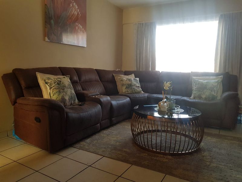 A comfortable living room area featuring tiled flooring and a large window that allows for natural light.