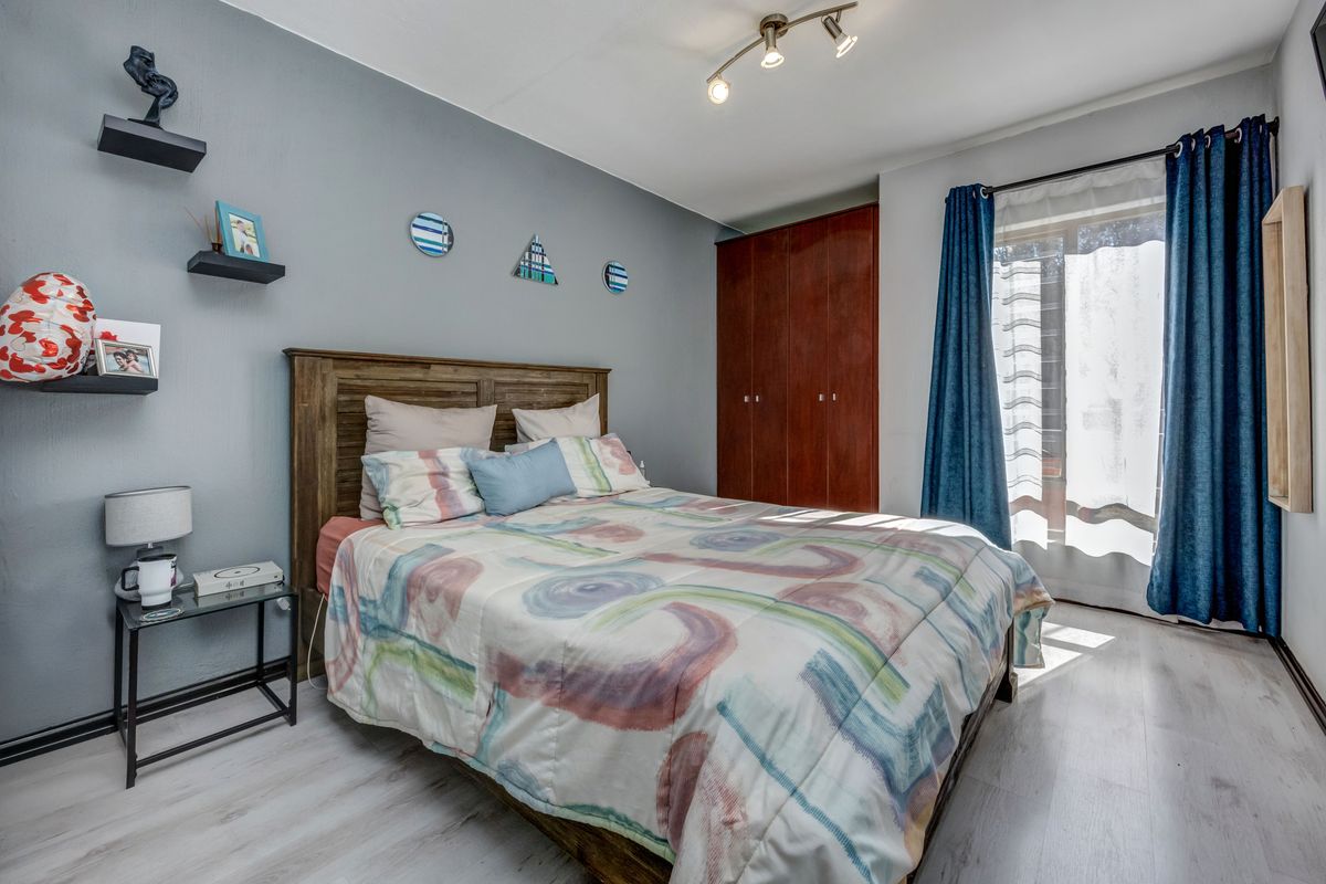 A well-maintained bedroom featuring laminate flooring, a built-in wardrobe, and a modern ceiling spotlight fixture, offering a comfortable and functional living space.
