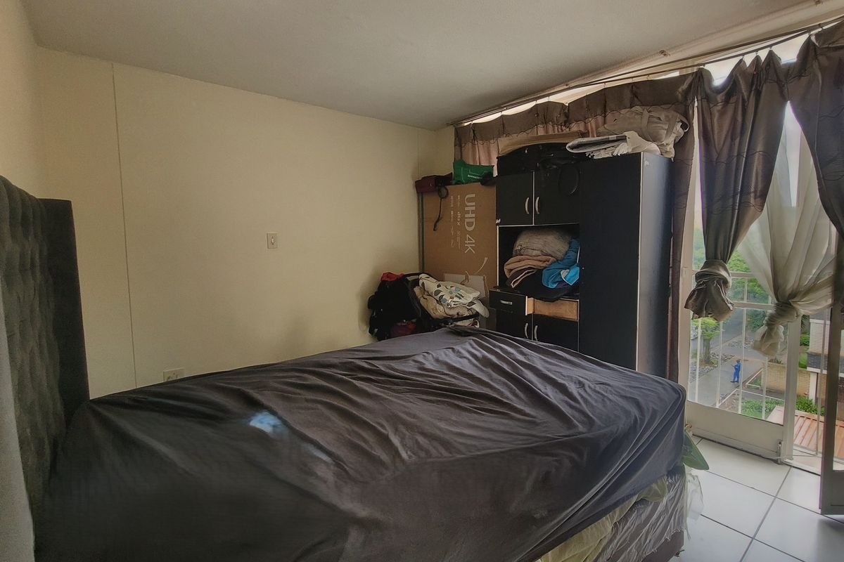 A bedroom featuring tiled flooring and a sliding glass door providing access to an outdoor balcony area.