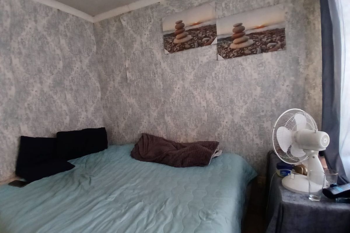 A bedroom featuring patterned wallpaper and a compact layout, currently showing signs of wear and requiring cosmetic updates to improve its overall appeal.