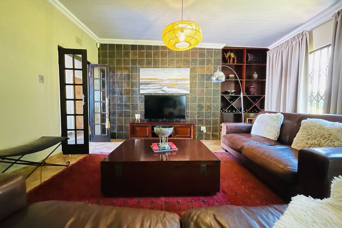 A comfortable living room featuring a tiled feature wall, built-in wooden shelving, and classic French doors leading to an adjacent space.