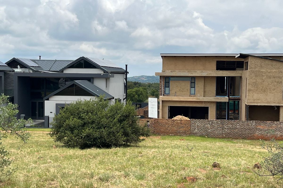 A view of a vacant residential plot featuring surrounding established homes and a neighboring property currently under construction.