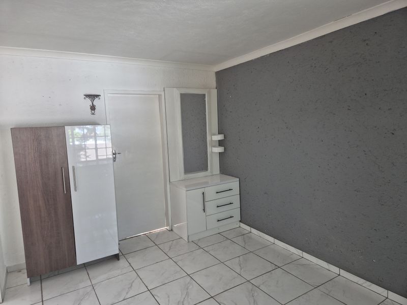 A bedroom featuring tiled flooring, a textured grey feature wall, and coving detail.