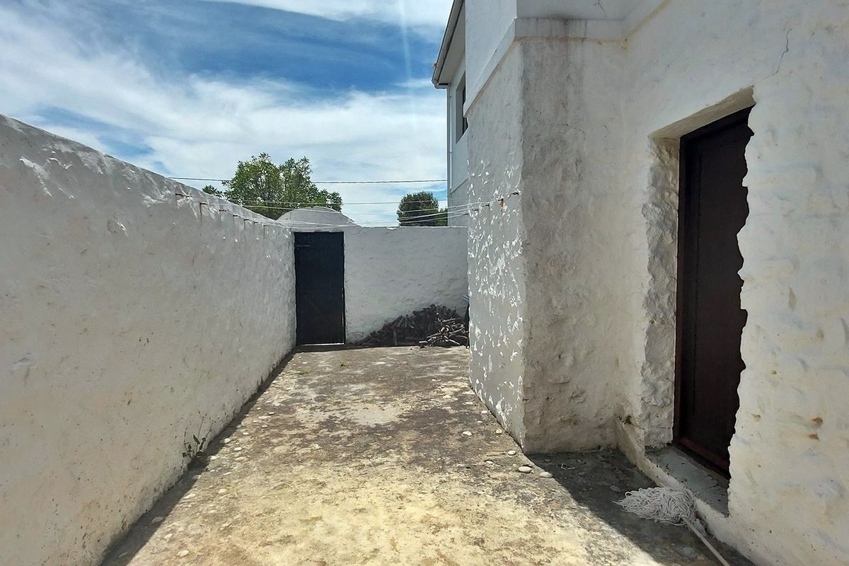 A private rear courtyard area featuring white-washed stone boundary walls and a concrete patio surface.