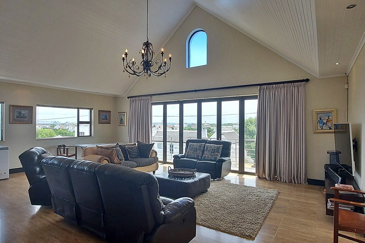 Spacious living room featuring a high vaulted tongue and groove ceiling, tiled flooring, and large bi-fold doors leading to an outdoor area.