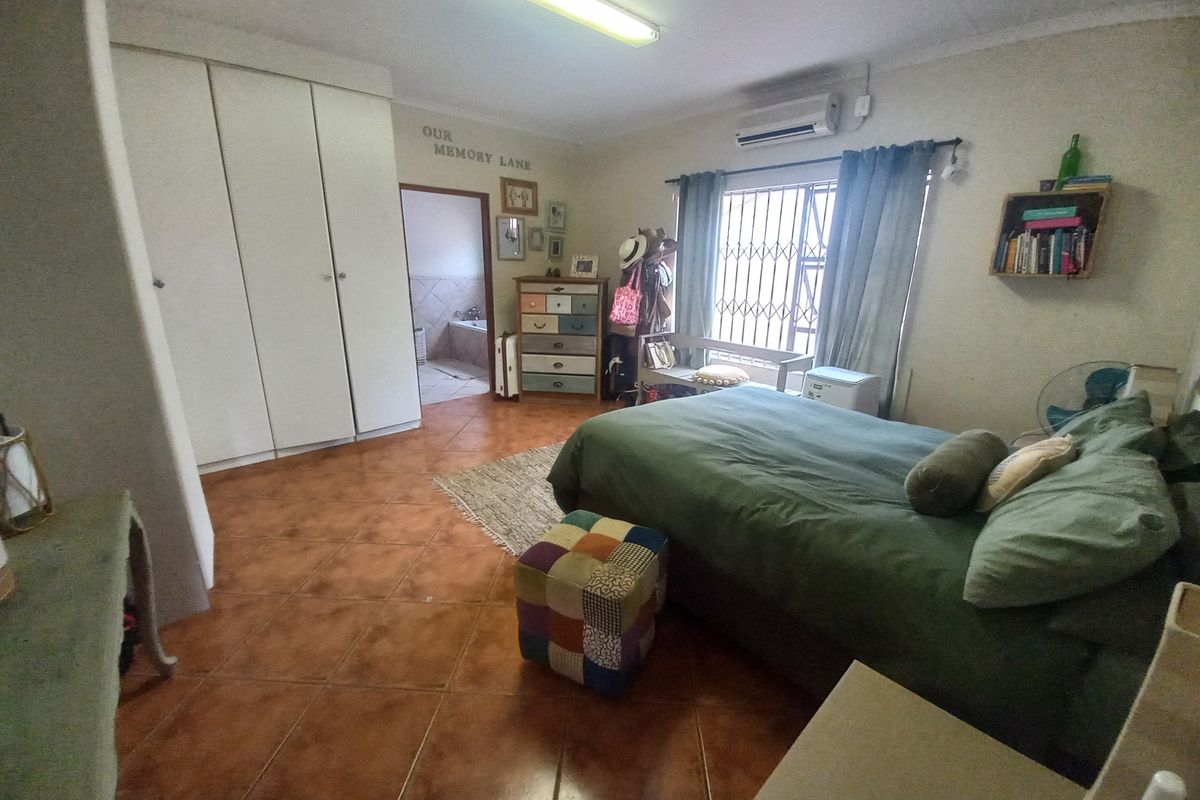 Spacious bedroom featuring tiled flooring, built-in cupboards, an air conditioning unit, and direct access to an en-suite bathroom.