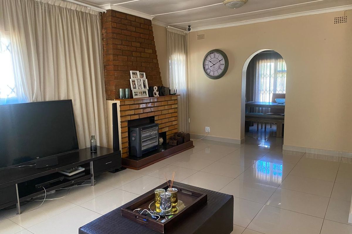 Spacious living room featuring a prominent brick fireplace, tiled flooring, and an arched doorway leading to the adjacent dining area.