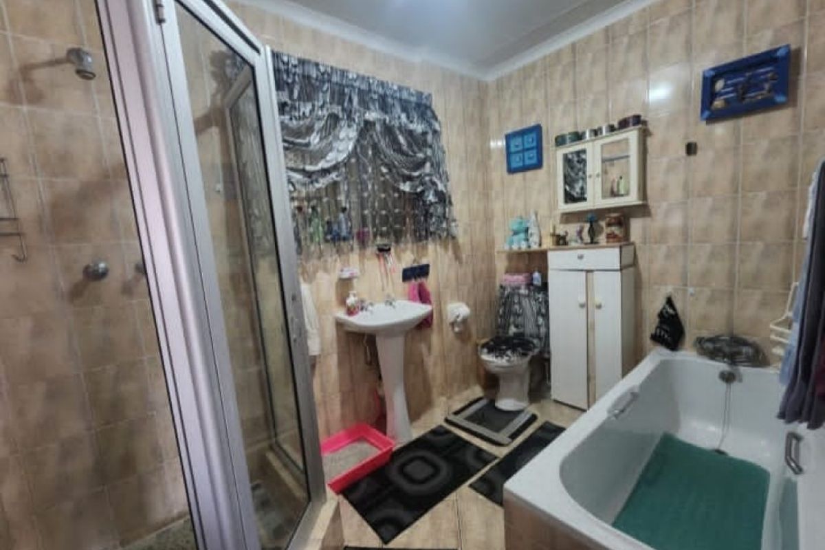 A functional bathroom featuring a pedestal basin, a separate shower enclosure, and a built-in bathtub with fully tiled walls and flooring.