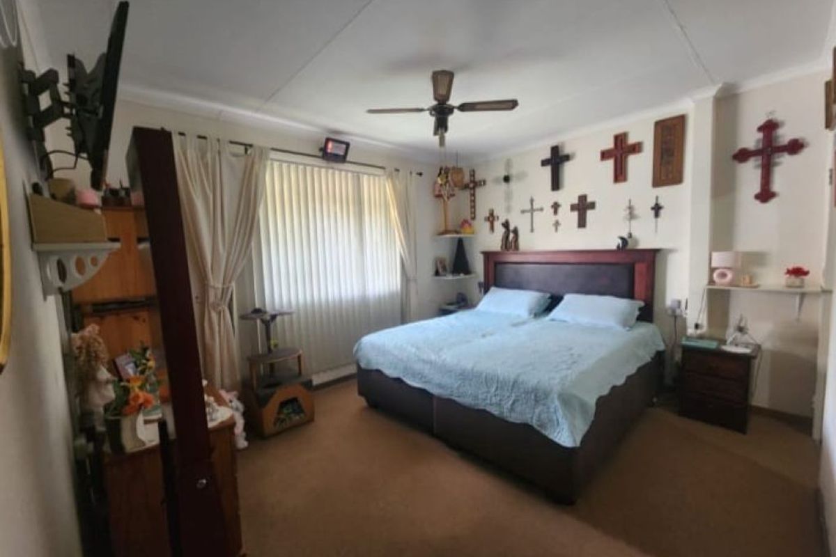 A standard bedroom featuring a ceiling fan, vertical blinds, and built-in shelving, providing a functional space with neutral wall finishes.