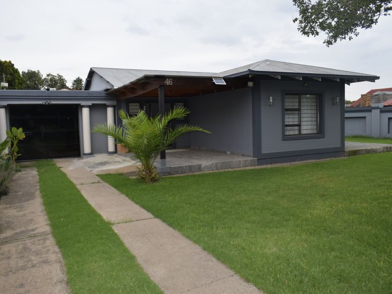 Front view of a single-story house featuring a garage, covered entrance patio, and a well-maintained lawn with a concrete driveway.