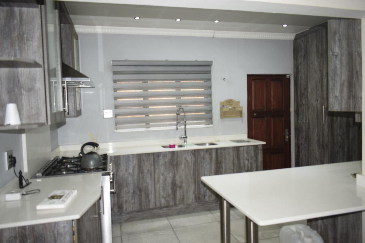 Modern kitchen featuring dark wood-grain cabinetry, stone countertops, a gas hob with extractor, and recessed lighting.