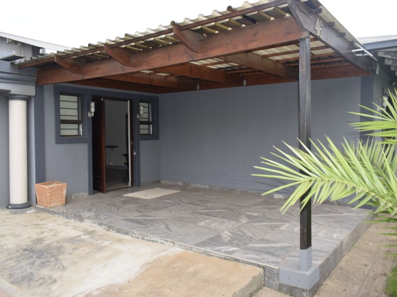 A covered patio area featuring a timber pergola, tiled flooring, and direct access to the home interior.