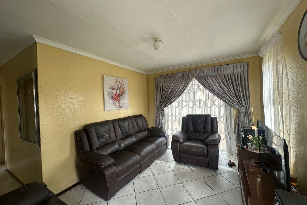 A living room featuring tiled flooring, large windows with curtains, and standard ceiling finishes.