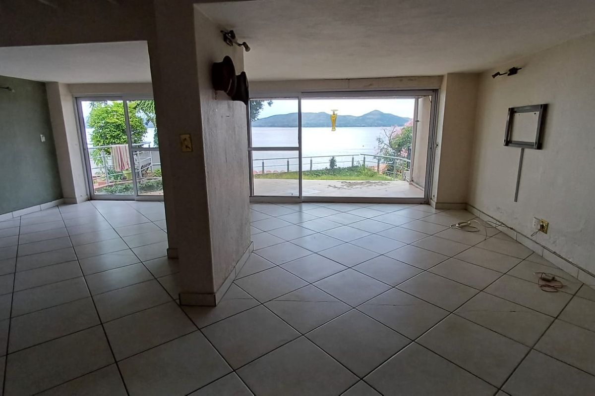 Spacious, empty living area featuring large sliding glass doors that provide natural light and direct access to a patio with scenic water views.