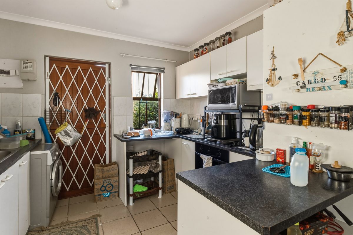 Functional kitchen featuring built-in cabinetry, laminate countertops, integrated oven, and tiled flooring with direct access to an exterior security door.