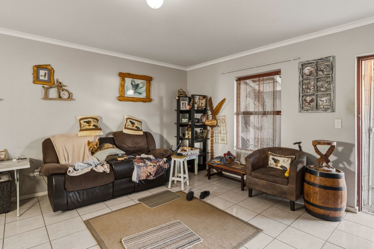 A living room featuring neutral wall paint and tiled flooring, providing a functional and well-lit space for relaxation.