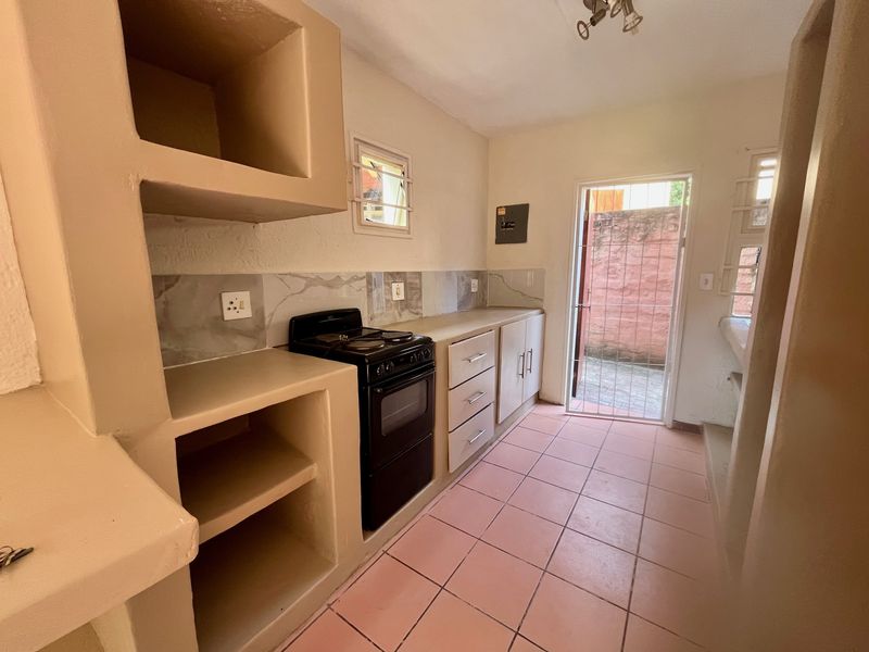 A functional kitchen featuring built-in masonry cabinetry, a freestanding stove, tiled flooring, and direct access to an exterior courtyard area.