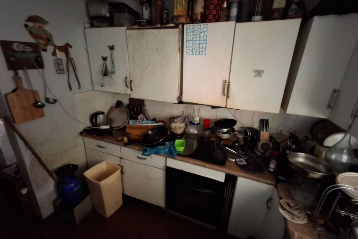 A dated kitchen featuring built-in cabinetry, a built-in oven, and tiled backsplash, requiring significant refurbishment and modernization to improve functionality and aesthetic appeal.