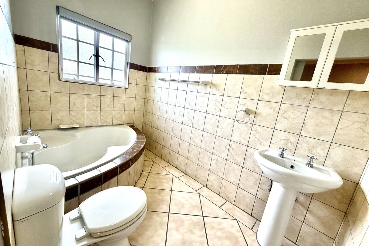 A functional bathroom featuring a corner bathtub, pedestal basin, and tiled finishes, offering a clean and practical layout for renovation or modernization.