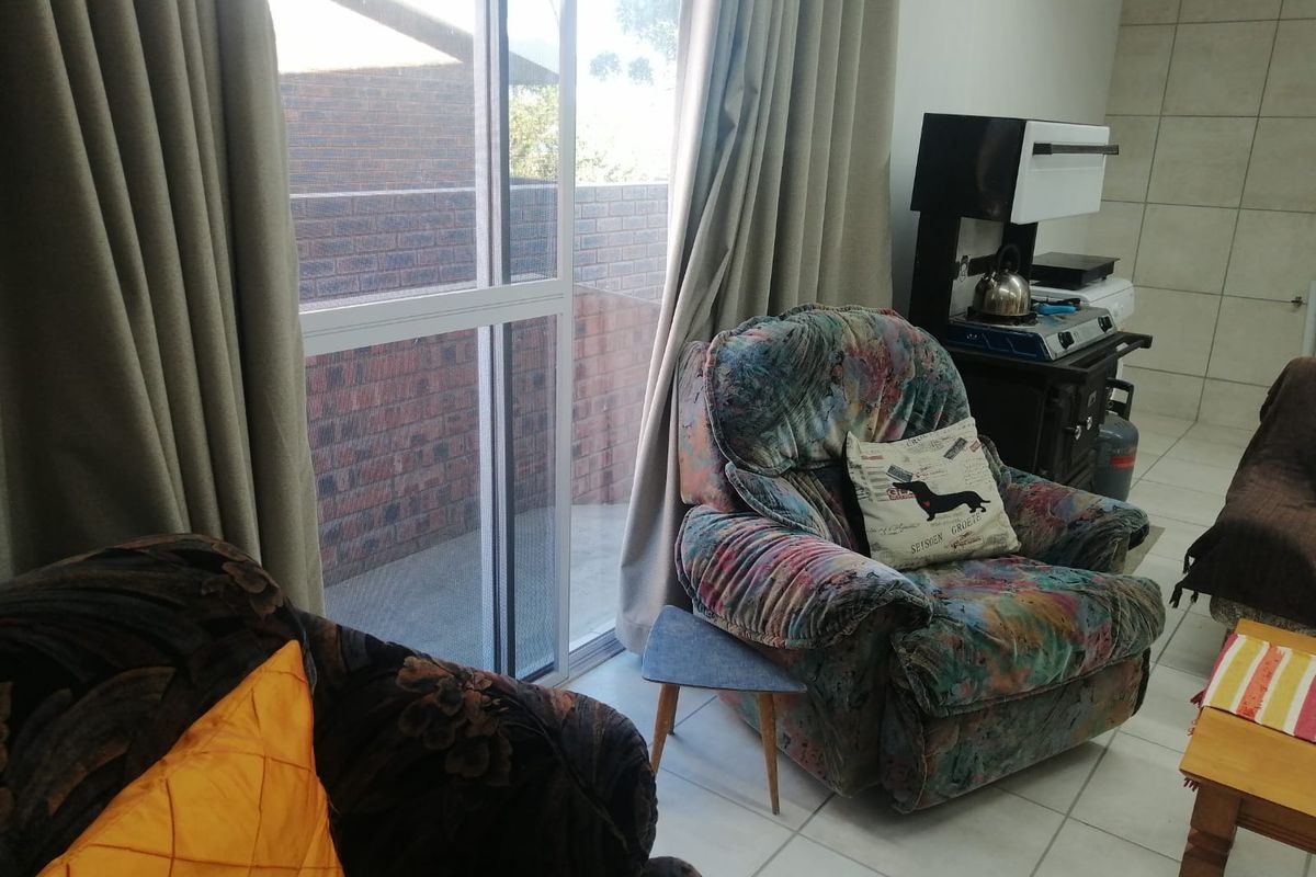 A living area featuring ceramic floor tiles and a large sliding glass door providing access to the exterior.