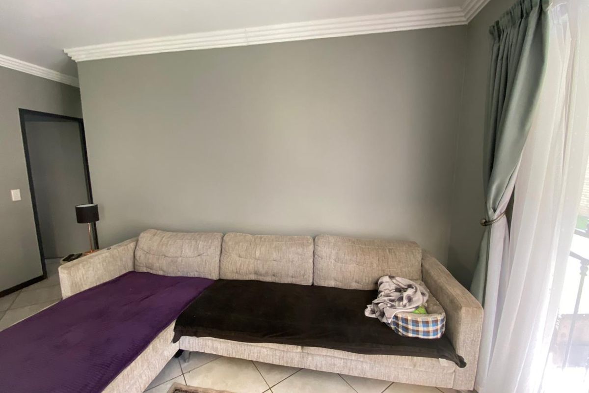 A living room area featuring neutral wall tones, crown molding, and tiled flooring, providing a clean foundation for interior design.
