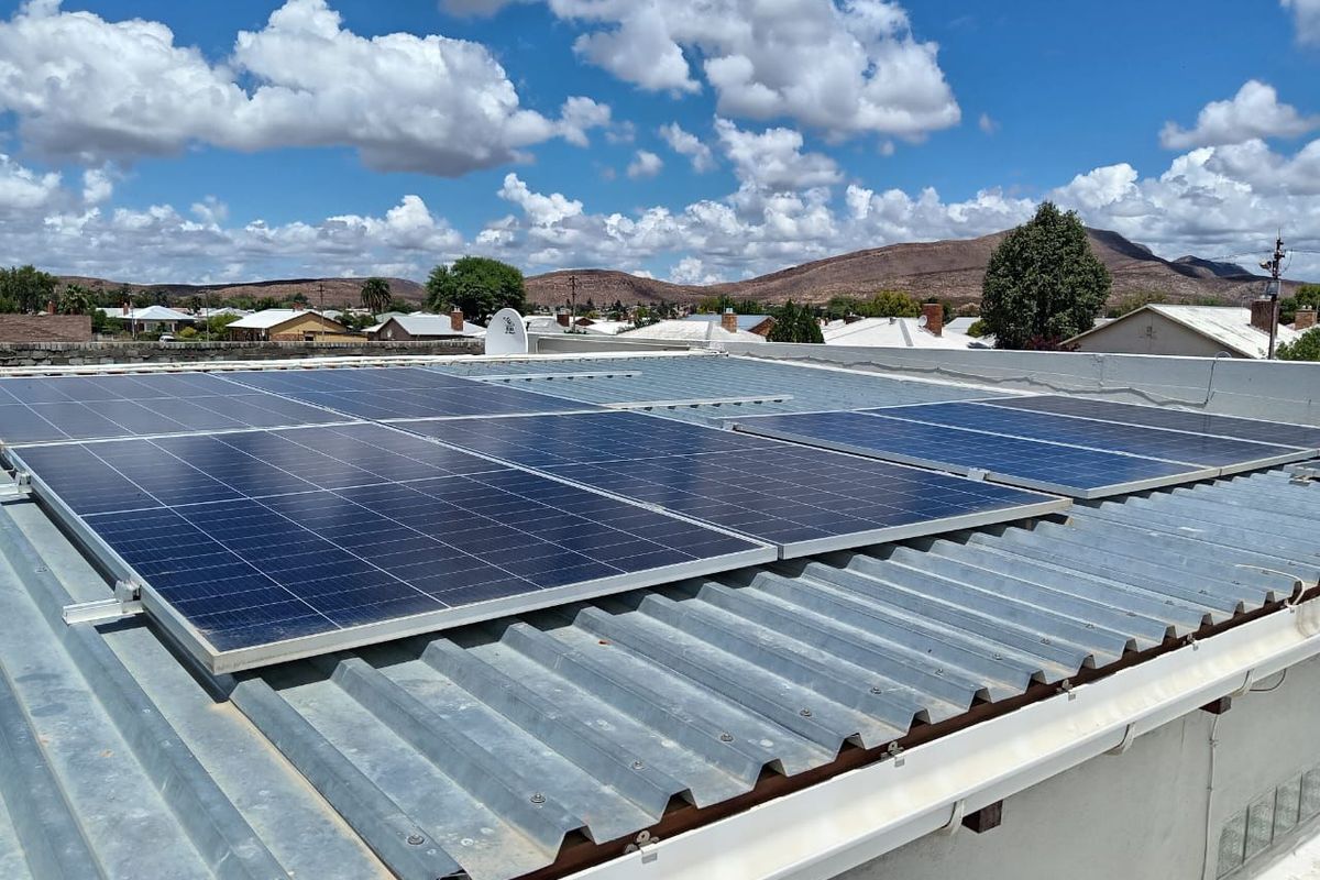 A view of the property roof featuring a mounted solar panel array, overlooking the surrounding neighborhood and distant mountain landscape.