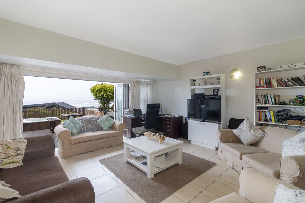 Spacious living room featuring tiled flooring and large sliding glass doors that open onto an outdoor patio area with ocean views.