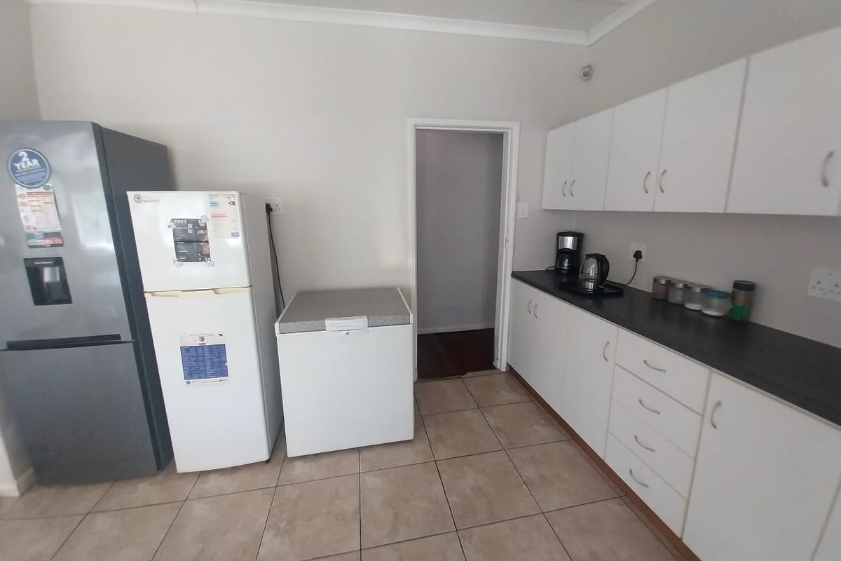 A functional kitchen featuring white cabinetry, dark countertops, and tiled flooring, providing ample storage and workspace.